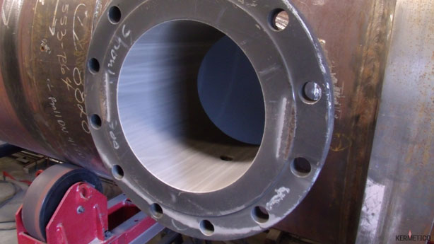 Close-up of a large metal pipe flange with bolt holes and a hollow bore.