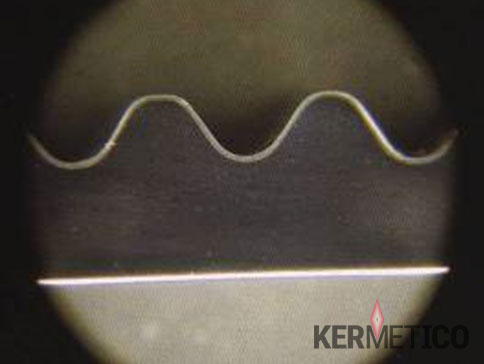 Microscope image of a circular field showing a white sine-wave line across the upper portion and a thin horizontal line along the bottom.