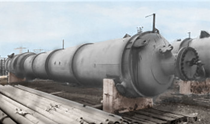 Row of large horizontal industrial tanks on concrete supports outdoors under a blue sky.
