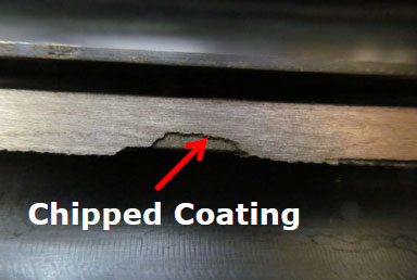 Close-up of a chipped coating on a metal surface with a red arrow pointing to the damaged area.