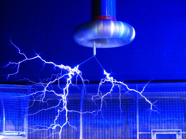 Blue electrical arcs from a high-voltage Tesla coil in a laboratory.