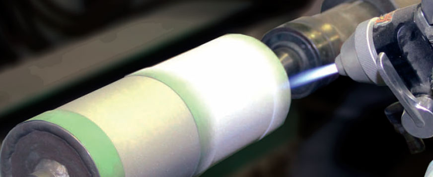 Close-up of a white roller with a green edge mounted on a metal machine.