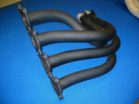 Black metal exhaust header with multiple curved tubes and a mounting flange on a blue background.