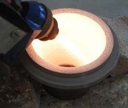 Close-up of a round container with a glowing peach-colored interior and a blue-and-orange nozzle on the side.