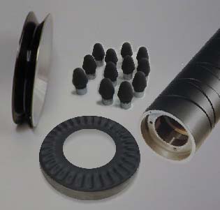Disassembled camera lens parts laid out on a white surface, including the lens barrel, a rubber gasket, a textured ring, and small spacers.