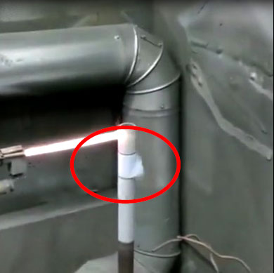 Close-up of a white PVC pipe joint circled in red, with gray metal ducts nearby in a utility space.