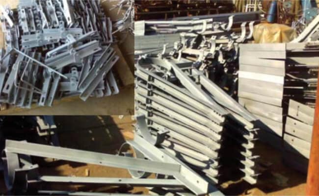 Piles of metal scaffolding frames and beams scattered in an outdoor yard.