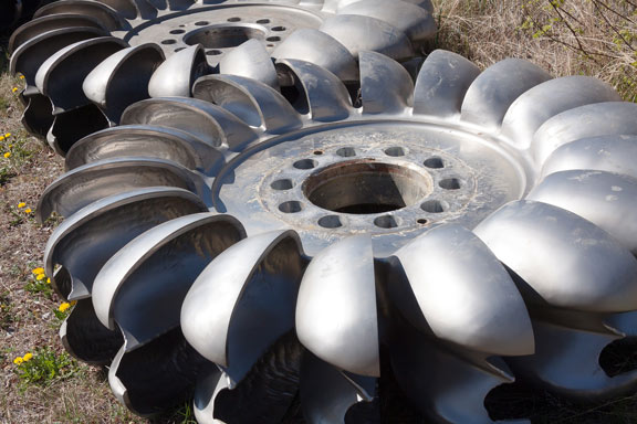 Two large metal centrifugal pump impellers with curved blades resting on the ground.
