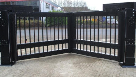 Corner of a balcony with black metal railing and beige tiled floor, overlooking a street.