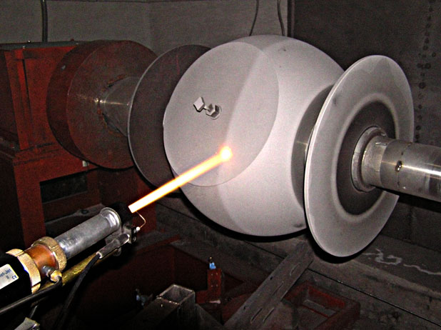 Laser beam aimed at a white spherical object mounted on a spindle in a lab setup.