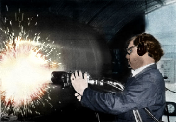 A man in a suit and sunglasses fires a large rocket launcher, with bright sparks flying in a dark tunnel.