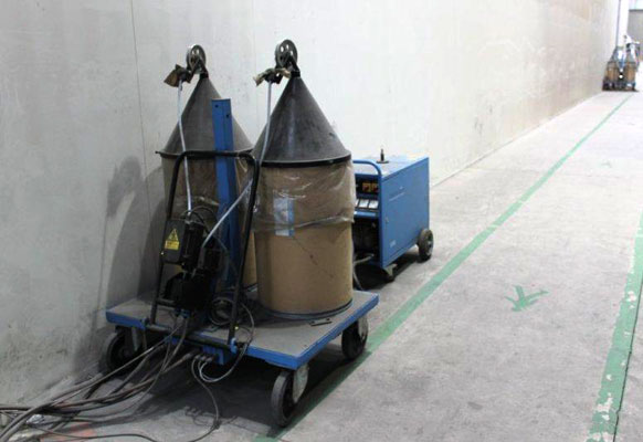 Two cyclone dust collectors on a wheeled platform with hoses in an industrial workshop.