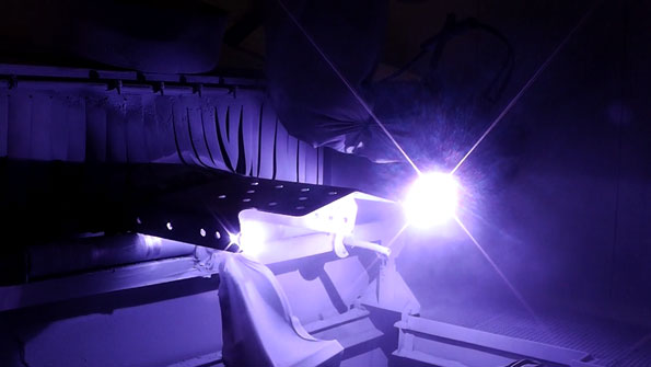 White, angular architectural blocks bathed in purple light with a bright starburst flare in the background.