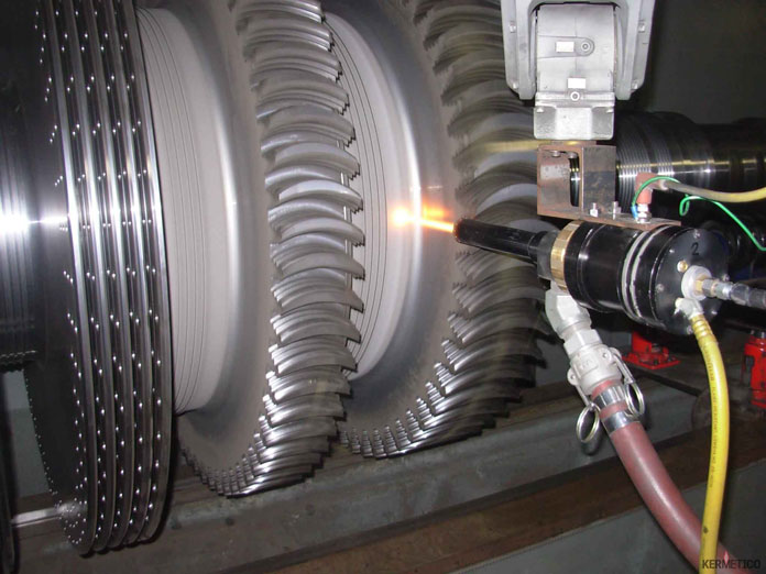 Close-up of a turbine rotor with a welding torch emitting a bright flame near the blades.