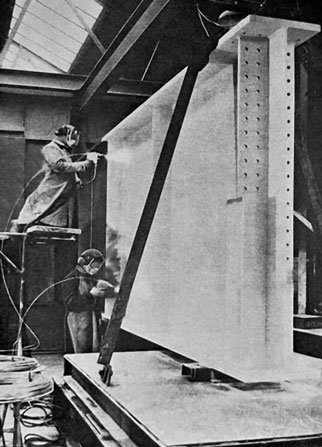 Two construction workers wearing hard hats guide a large vertical panel into place within a steel framework.